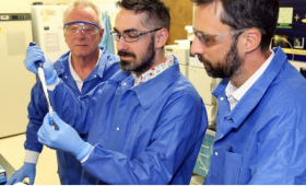 Three scientists examine an injection vial