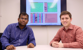 Two scientists in front of screen displaying computer data