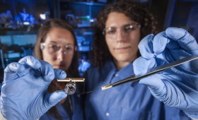 Two researchers hold a brain-on-a-chip device