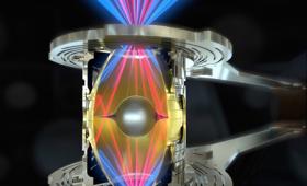 Lasers beaming into a gold rugby hohlraum holding an aluminum fuel capsule.