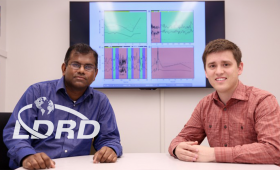 Two scientists in front of screen displaying computer data