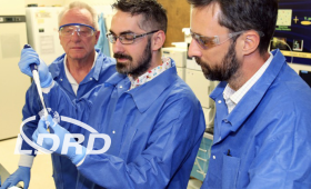 Three scientists examine an injection vial