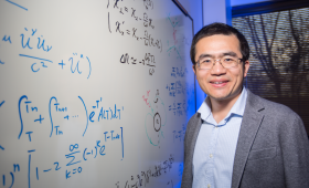 Yuan Shi standing by white board with algorithms