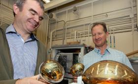 Two scientists hold photomultiplier tubes