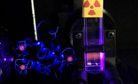 Plastic vial containing radioactive curium and the protein lanmodulin, glowing during a fluorescence spectroscopy experiment.