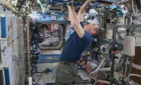 Astronaut inside space station surrounded by equipment reaching up